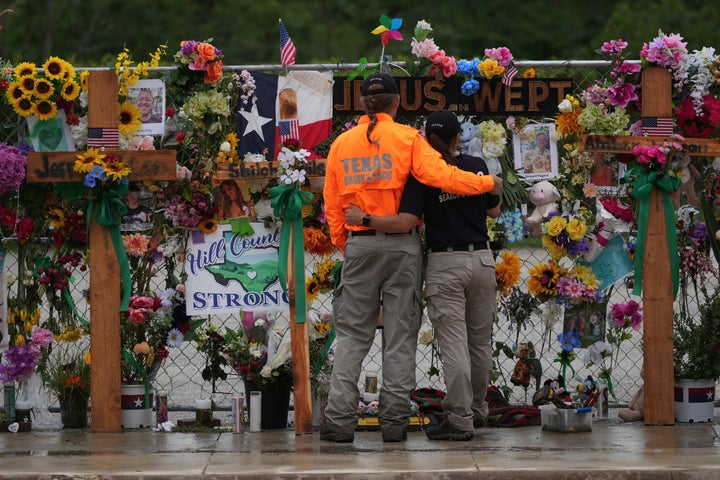 Membros de uma equipe de busca e resgate abraçam enquanto visitam um muro memorial para vítimas de inundações, em 13 de julho de 2025, em Kerrville, Texas.