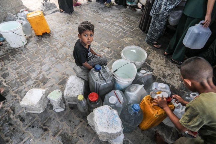 Israeli Airstrike Kills Youngsters Accumulating Water As Gaza Disaster Worsens 1 Displaced Palestinians fill containers with water from tankers brought into the area in Khan Younis, Gaza, on July 13, 2025.