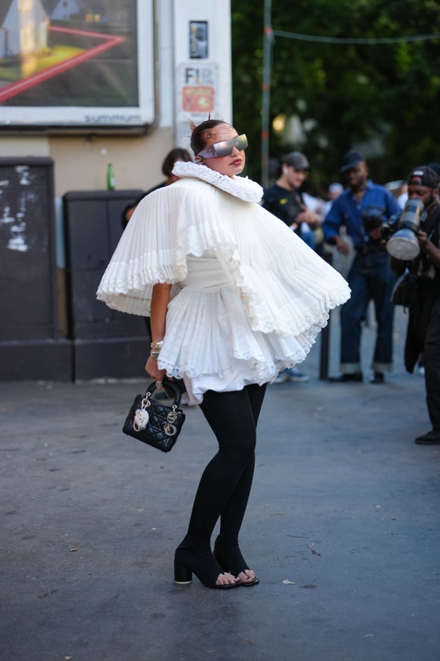 Καλεσμένη στην επίδειξη υψηλής ραπτικής του οίκου Magiela, φοράει ογκώδη λευκή πλισέ κάπα. 