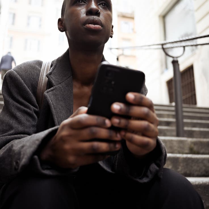 Stylish businesswoman reading messages on her smartphone while sitting on stairs