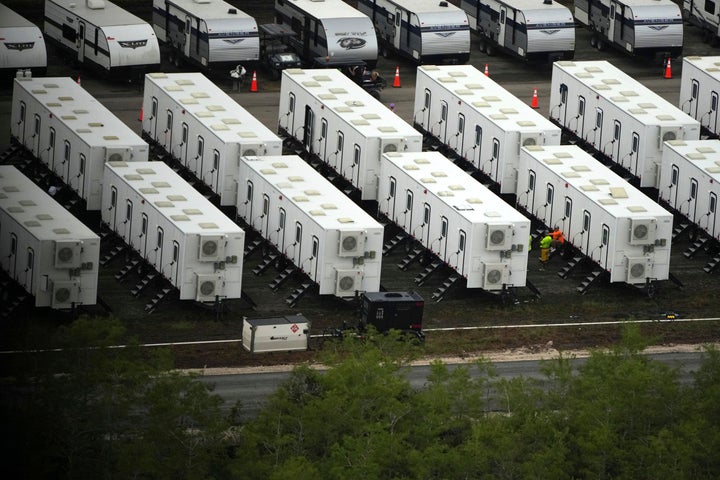 Workers sit alongside trailers as work progresses on a new migrant detention center dubbed "Alligator Alcatraz," at Dade-Collier Training and Transition facility in the Florida Everglades, Friday, July 4, 2025, in Ochopee, Fla. (AP Photo/Rebecca Blackwell)