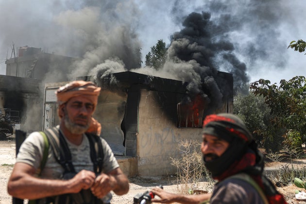 Βεδουίνοι μαχητές στέκονται μπροστά από ένα καμένο κατάστημα στο χωριό Mazraa στα περίχωρα της πόλης Sweida, κατά τη διάρκεια συγκρούσεων μεταξύ των φυλών των Βεδουίνων και της πολιτοφυλακής των Δρούζων, στη νότια Συρία, Παρασκευή 18 Ιουλίου 2025. (AP Photo/Ghaith Alsayed)