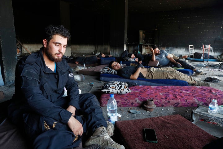 Syrian security forces rest inside a burned shop as they get deployed to Mazraa, a village on the outskirts of the Druze-majority city of Sweida, Syria, on July 20, 2025.