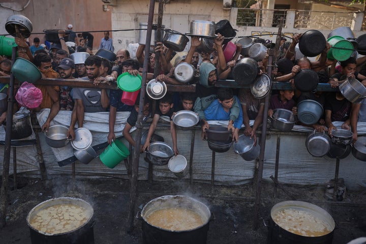 Palestinians struggle to get donated food at a community kitchen in Gaza City, northern Gaza Strip, Monday, July 14, 2025. (AP Photo/Jehad Alshrafi)