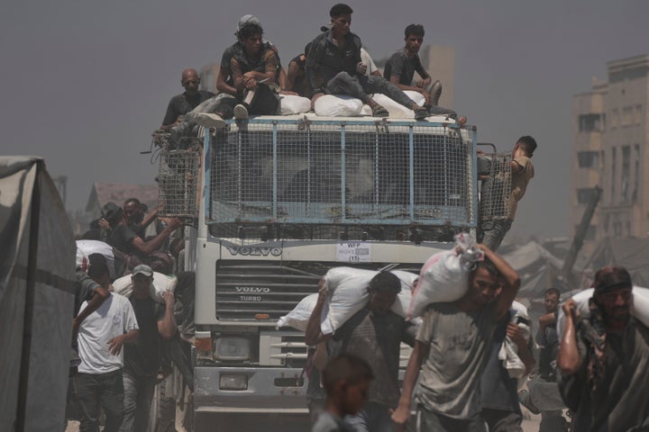 Israel Begins Every day Pause In Preventing In 3 Gaza Areas To Enable 'Minimal' Help As Starvation Grows 2 Palestinians carry sacks of flour unloaded from a humanitarian aid convoy that reached Gaza City from the northern Gaza Strip, Sunday, July 27, 2025. (AP Photo/Jehad Alshrafi)