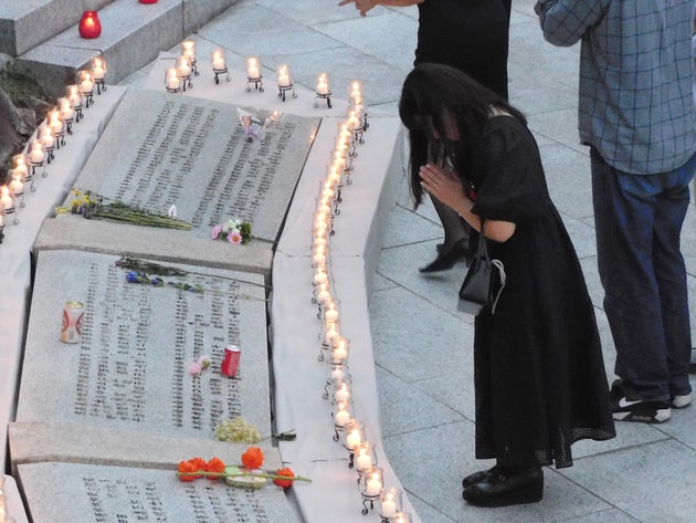 日航機墜落事故の追悼施設「慰霊の園」でろうそくをともし、祈りをささげる遺族＝2024年8月12日午後、群馬県上野村