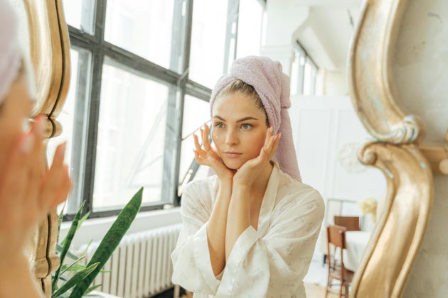 Woman examining face in mirror.