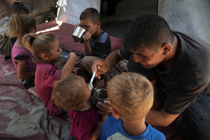 Fadi Sobh gives lentil soup to his children as they sit in their tent at a camp for displaced Palestinians in Gaza City, Thursday, July 24, 2025. (AP Photo/Jehad Alshrafi)