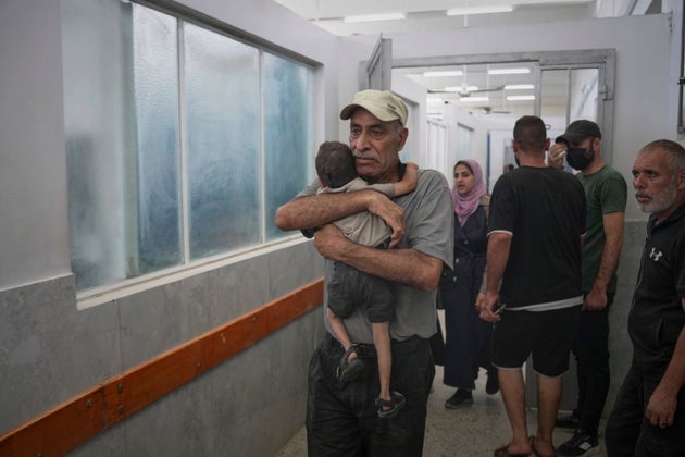 A man carries his grandson, wounded in an Israeli strike, at Shifa Hospital in Gaza City, Sunday, July 6, 2025. 