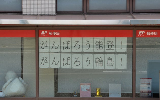 輪島市内の郵便局の窓に貼られていた「がんばろう能登！」（2025年7月20日）
