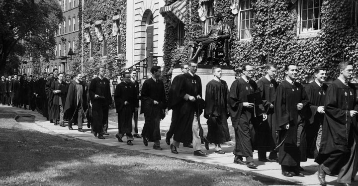 Siswa melewati patung John Harvard di Harvard Yard dalam perjalanan ke layanan sarjana muda menjelang dimulainya di Universitas Harvard pada 17 Juni 1951.