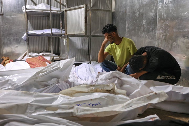 Palestinians mourn over the shrouded bodies of people killed the previous day while seeking aid near northern Gaza's Zikim, at the morgue of Al-Shifa Hospital in Gaza City on Aug. 10, 2025.
