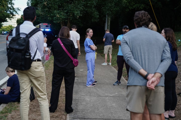 ATLANTA, GEORGIA - AUGUST 08: A woman wearing hospital scrubs is seen among a group of people near the Centers For Disease Control (CDC) Global Headquarters during an active shooter incident on August 8, 2025 in Atlanta, Georgia. According to the Atlanta Police Department, the suspect in the active shooter situation is dead and a police officer was injured.