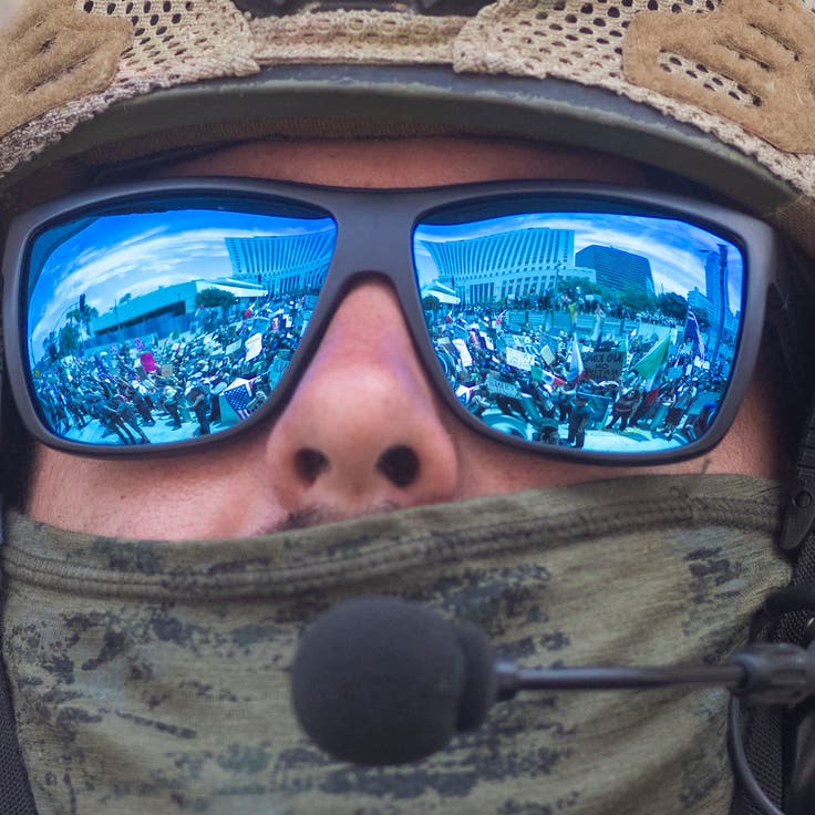 Protesters are seen reflected in the sunglasses of a U.S. Marine standing guard outside the Federal Building, during a protest against the Trump administration during the "No Kings" national rally in downtown Los Angeles, California, on June 14, 2025, on the same day as President Trump's military parade in Washington, DC. Tens of thousands of protesters rallied nationwide Saturday against Donald Trump ahead of a huge military parade on the US president's 79th birthday -- as the killing of a Democratic lawmaker underscored the deep divisions in American politics. "No Kings" demonstrators took to the streets in New York, Los Angeles, Chicago, Philadelphia, Houston, Atlanta and hundreds of other cities across the United States to condemn what they call Trump's dictatorial overreach. 