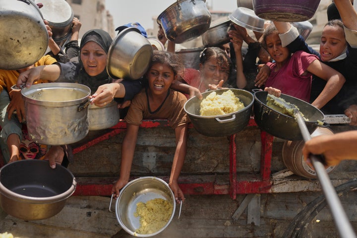 Palestinians struggle to get donated food at a community kitchen in Gaza City, northern Gaza Strip, Saturday, Aug. 16, 2025. (AP Photo/Jehad Alshrafi)