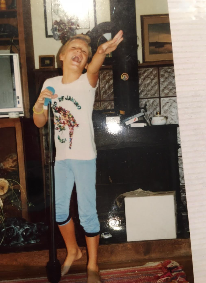 The author, age 8, performing at home with a microphone.