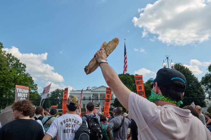 Um manifestante mantém um pedaço de pão em frente à Casa Branca, à medida que milhares marcharam através de Washington, DC, em protesto contra o uso de agentes federais por Trump e a Guarda Nacional para conduzir ações de policiamento em toda a cidade.