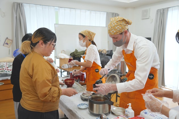 食事の配膳を手伝う、アメリカ人留学生のボランティア（右）