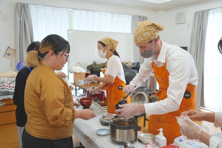 食事の配膳を手伝う、アメリカ人留学生のボランティア（右）