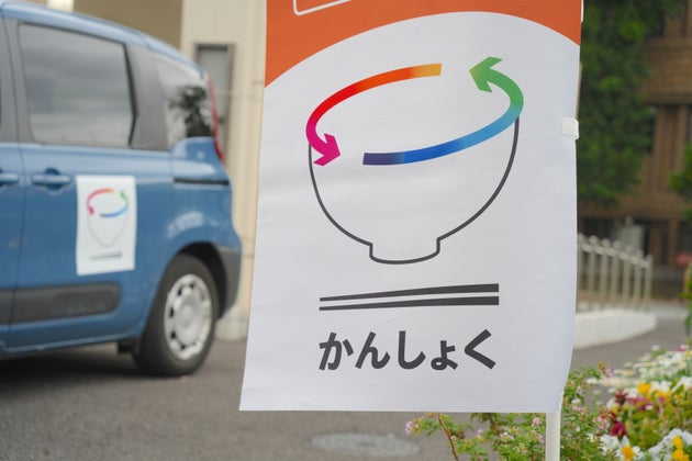 かんしょくプロジェクトの旗と食事運搬用の車両