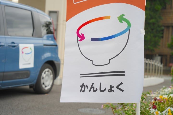 かんしょくプロジェクトの旗と食事運搬用の車両