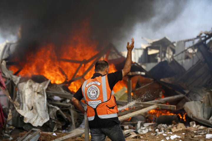 Palestinian Civil Defense teams and civilians respond to a massive fire sparked by an Israeli airstrike in the central Gaza city of Deir al-Balah, on Aug. 21, 2025.