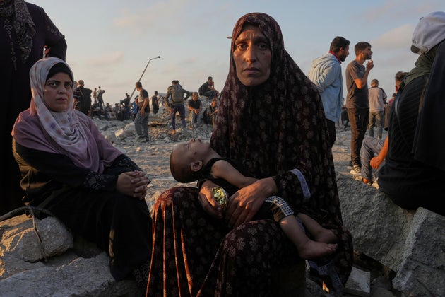 Somoud Wahdan looks at the camera while she and her child wait for trucks of humanitarian aid to arrive in Gaza City, July 25, 2025.