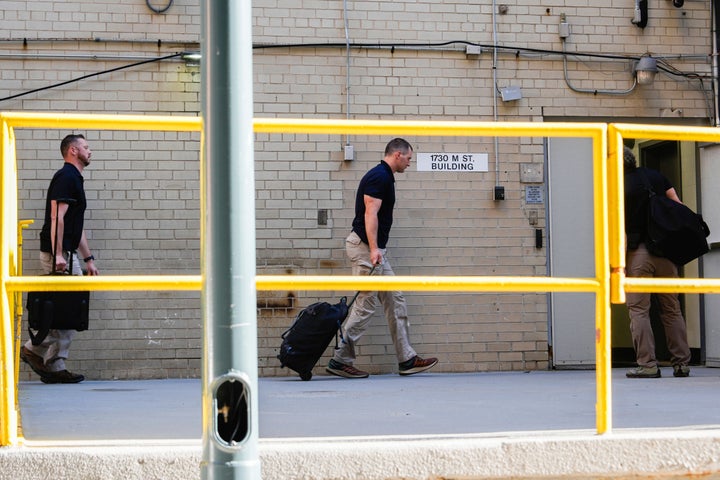 FBI agents walk in the back entrance of Bolton's Washington office on Friday.