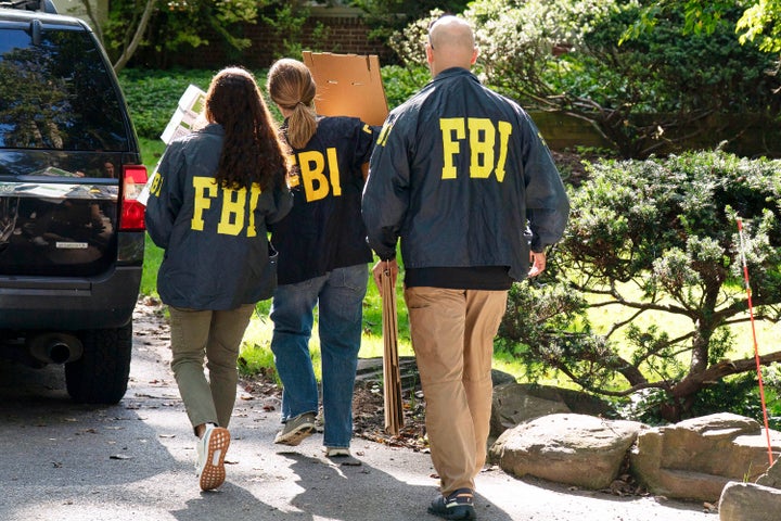 Os agentes do FBI carregam caixas vazias na casa de Bolton como parte de sua pesquisa autorizada pelo tribunal.