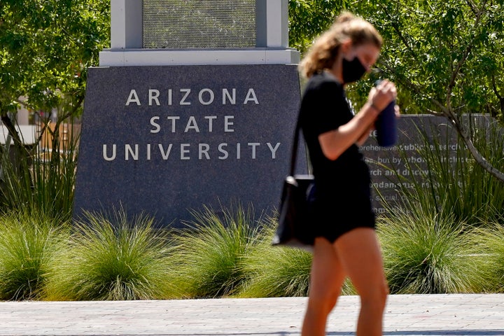 A pedestrian crosses a typically busy intersection on the campus of Arizona State University on Tuesday, Sept. 1, 2020, in Tempe, Ariz. (AP Photo/Matt York)