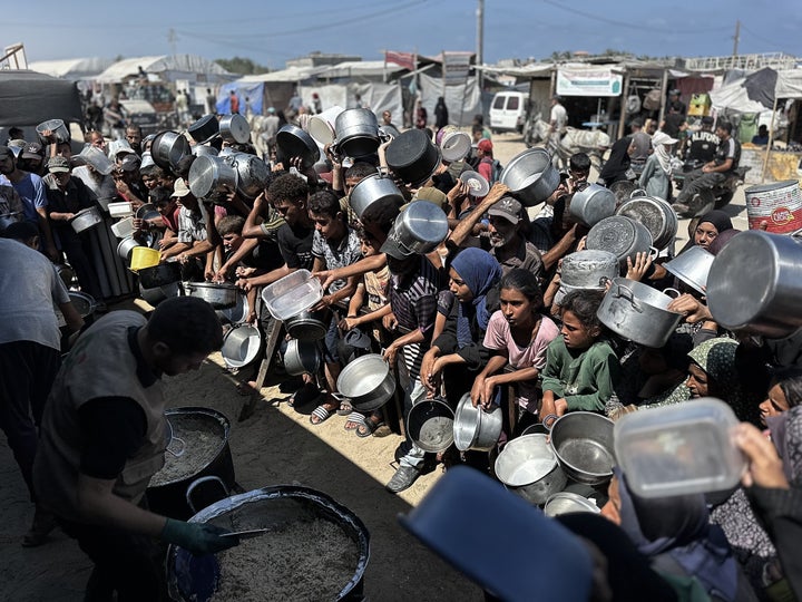 Palestinians, including children, who are struggling to access food due to Israel's blockade and ongoing attacks on the Gaza Strip, wait in line to receive hot meals distributed by the charity organization at Al-Mawasi area in Khan Yunis, Gaza on August 23, 2025. (Photo by Doaa Albaz/Anadolu via Getty Images)