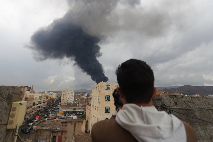 A journalist photographs billowing smoke from an Israeli airstrike on the Yemeni capital of Sana'a, on Aug. 24, 2025. The Israeli army said it targeted Houthi military sites in the city, including areas near the presidential palace, along with power plants and a fuel storage facility.