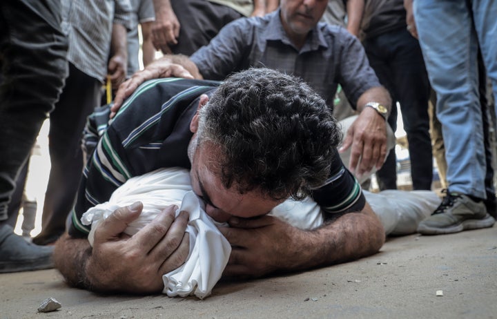 A man embraces the shrouded deceased as Palestinians' bodies are brought to Al-Shifa Hospital for funeral procedures following Israeli military attacks in various areas of Gaza City, on Aug. 24, 2025.