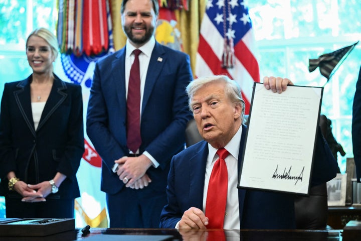 Donald Trump holds up one of the executive orders he signed that aims to end cashless bail.
