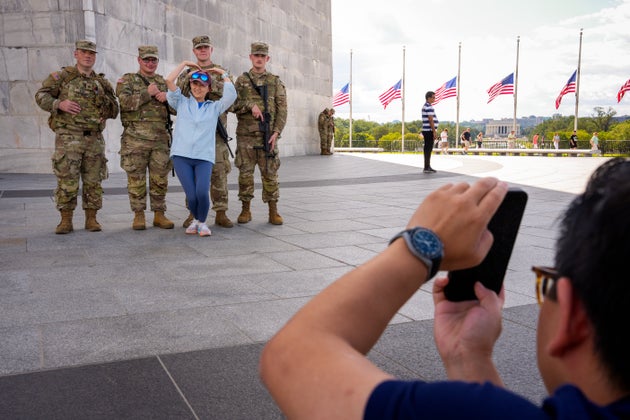 A tourist visiting from Shenzhen, China, poses for a photograph with armed members of the National Guard at the National Mall on Wednesday in Washington, D.C.
