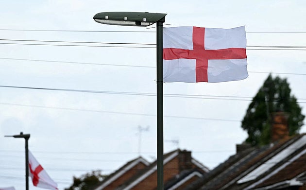 St George's Cross flags, the national flag of England, fly from lamp posts outside houses on a residential street in Stanwell, west London on August 27, 2025. 