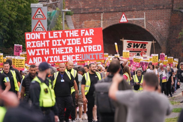 Demonstrator hold placards and banners as they march to the Bell Hotel in Epping, near London, Sunday, July 27, 2025.