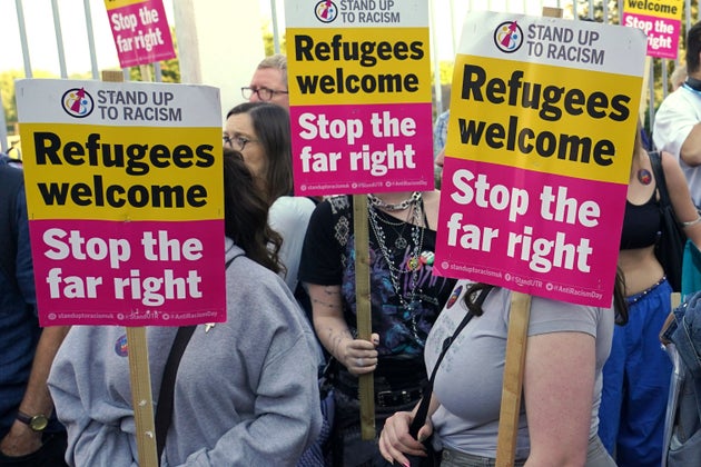 Protesters hold placards during a demonstration in Orpington near London, Friday, Aug. 22, 2025