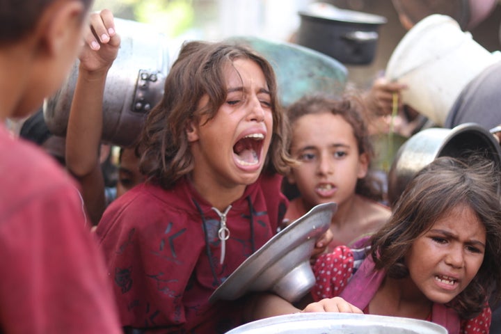 Palestinian children holding empty pots wait to receive food distributed by a charity in Nuseirat camp as Israel continues to block access to most aid, on Sept. 4, 2025.