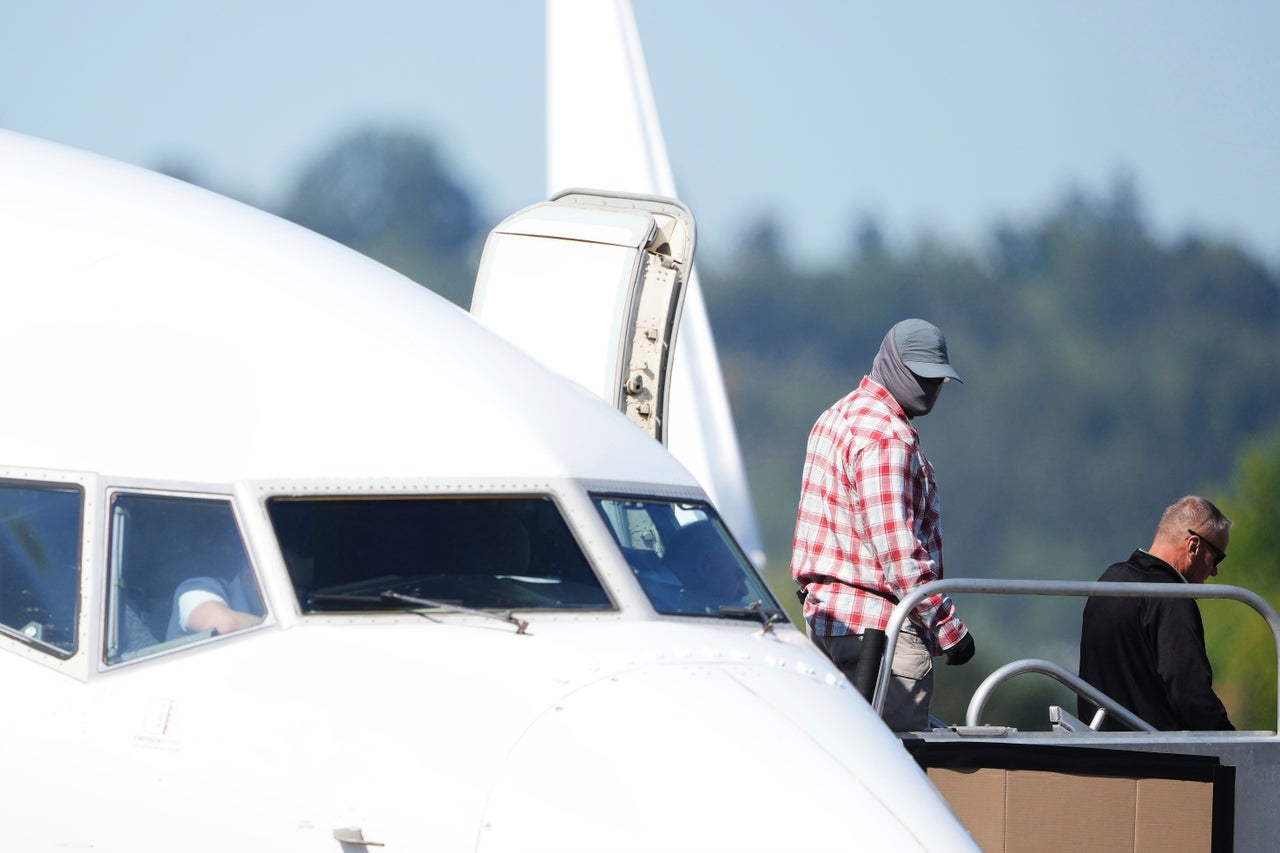 A worker in a mask walks off a U.S. Immigration and Customs Enforcement flight departing from King County International Airport-Boeing Field in Seattle on Aug. 23.
