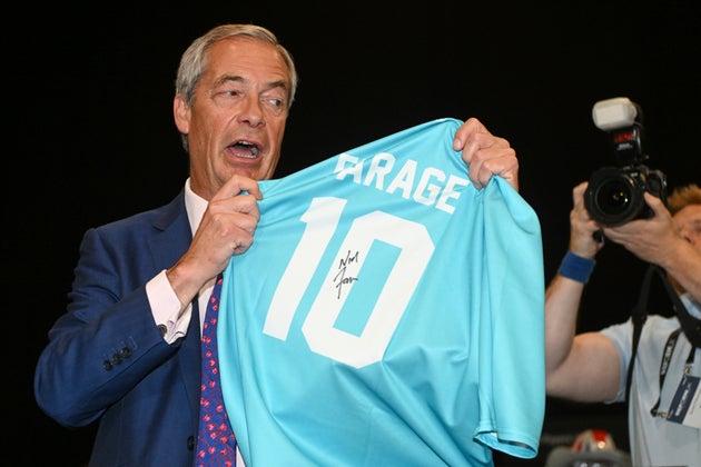 Britain's Reform UK party leader Nigel Farage holds a shirt signed by him during the Reform party's annual conference.
