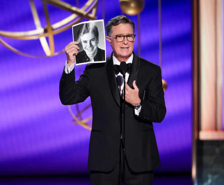 Stephen Colbert holds up his vintage headshot as he jokes about his late-night show's cancellation during the 77th Primetime Emmy Awards.