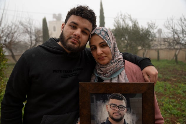 Amir, 22, cries and holds Mona, 36, mother of 17-year-old Tawfiq Abdel Jabbar, a teenager from Louisiana who was fatally shot by Israeli forces last week, while they pose with a framed photo of him at the family's West Bank village of Al-Mazra'a ash-Sharqiya, on Jan. 23, 2024.