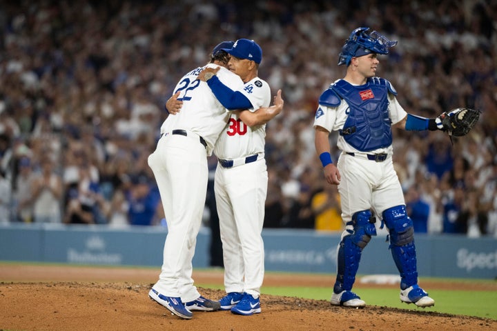 Los Angeles Dodgers starting pitcher Clayton Kershaw, left, hugs manager Dave Roberts, center, after being removed during the fifth inning of a baseball game against the San Francisco Giants, in Los Angeles, Friday, Sept. 19, 2025. (AP Photo/Kyusung Gong)
