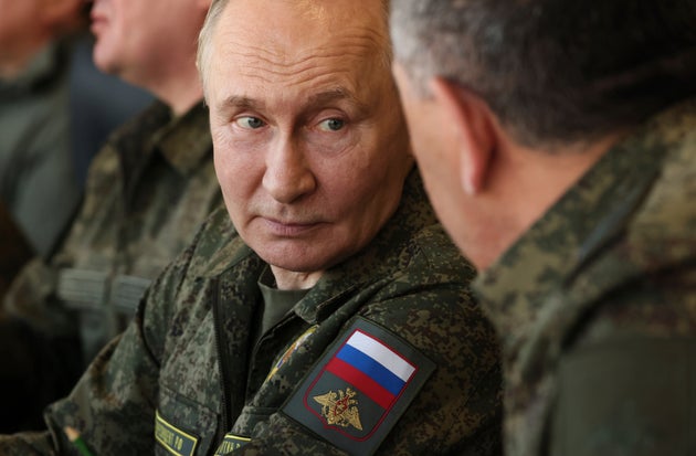 Russian President Vladimir Putin listens to Deputy Defence Minister Yunus-Bek Yevkurov, back to a camera, during the Russian-Belarusian joint military drills 