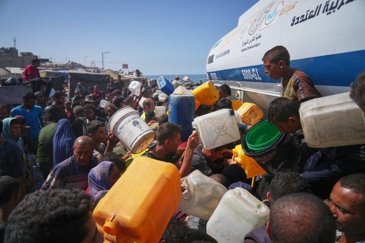 Displaced Palestinians gather to collect water from a truck at a makeshift camp in Nuseirat, central Gaza Strip, Thursday, Oct. 2, 2025.(AP Photo/Abdel Kareem Hana)