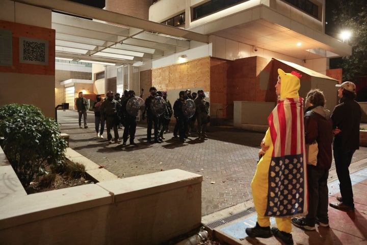 People protest outside a U.S. Immigration and Customs Enforcement facility as federal agents walk down a driveway, in Portland, Oregon, Wednesday, Oct. 1, 2025. (AP Photo/Amanda Loman)
