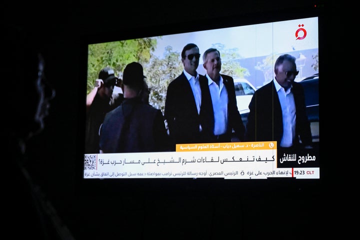 An Egyptian woman watches the news on a local channel in Cairo on October 8, 2025, showing images of the US president's Middle East envoy Steve Witkoff (R) and son-in-law Jared Kushner (C) arriving in Sharm El-Sheikh for talks on ending the Gaza war. Negotiators from the Palestinian Hamas movement and Israel began on October 6 indirect talks in the Egyptian resort town of Sharm El-Sheikh over a US-proposed plan for ending the nearly two-year war in Gaza, Egyptian state-linked media reported. (Photo by Khaled DESOUKI / AFP) (Photo by KHALED DESOUKI/AFP via Getty Images) 