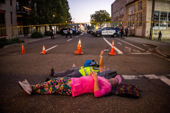 People relax on a street outside a U.S. Immigration and Customs Enforcement facility on Tuesday, Oct. 7, 2025, in Portland.