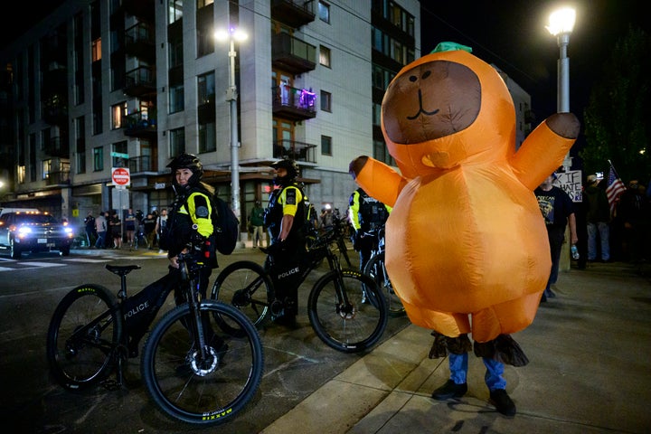 Portland Police officers stand watch as protesters demonstrate near an Immigration and Customs Enforcement facility in downtown Portland, Oregon, on Oct. 6, 2025.